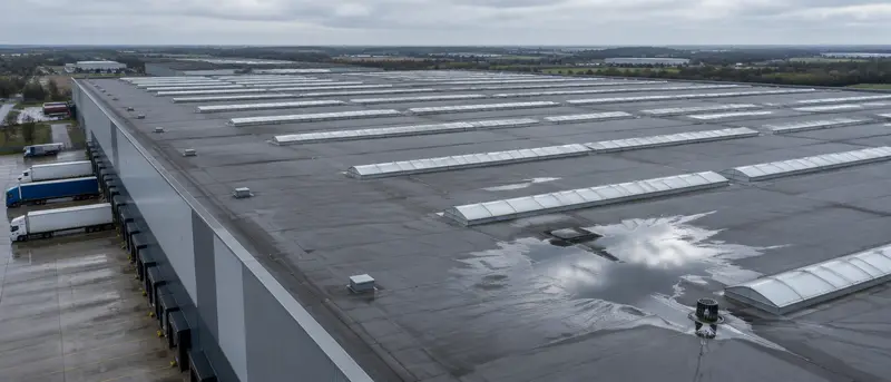Ponding water on a warehouse roof near an outlet